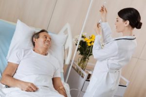 Nurse standing by a patient's bedside and hanging an IV