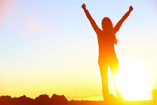 Happy celebrating winning success woman at sunset or sunrise standing elated with arms raised up-img-blog