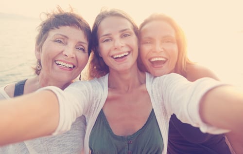 mother and two adult daughters are doing selfe on the beach-img-blog