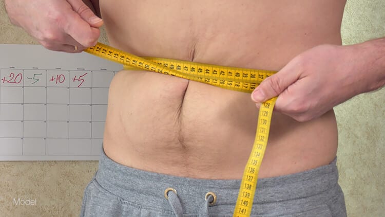 A man measures his waist to see the extra inches he's gained. Non-invasive procedures that target extra fat can be useful in reducing extra fat along the abdomen for men.