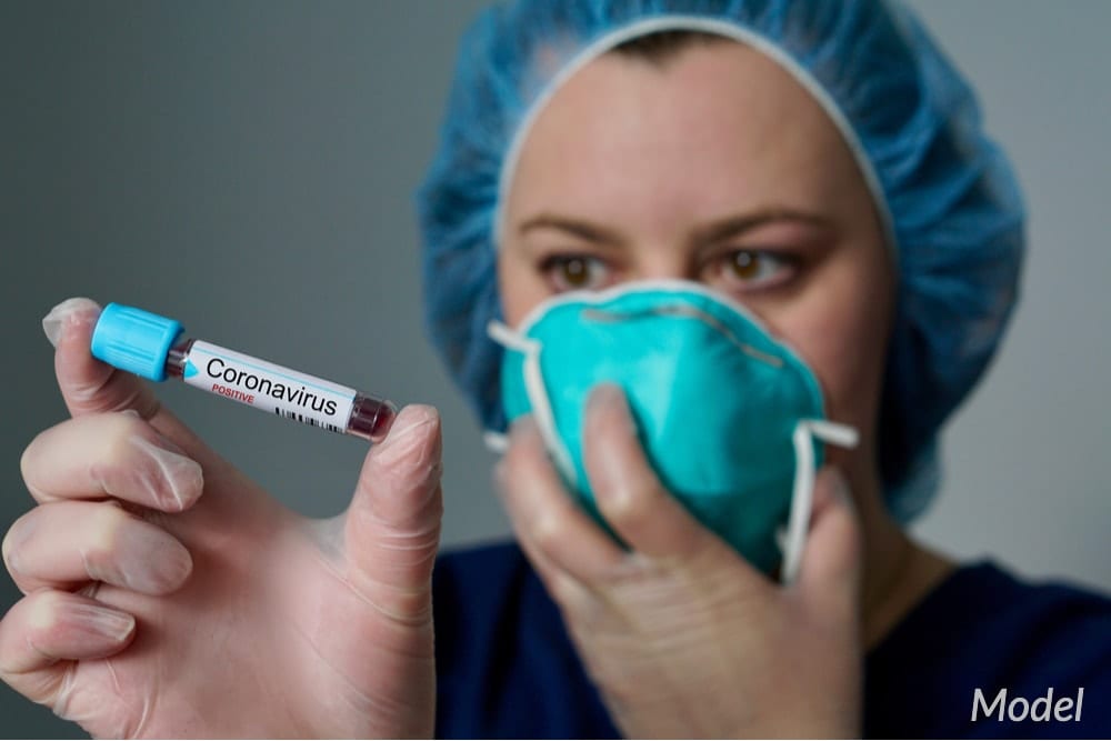 Nurse with covered mouth and nose holding a blood sample that has coronavirus