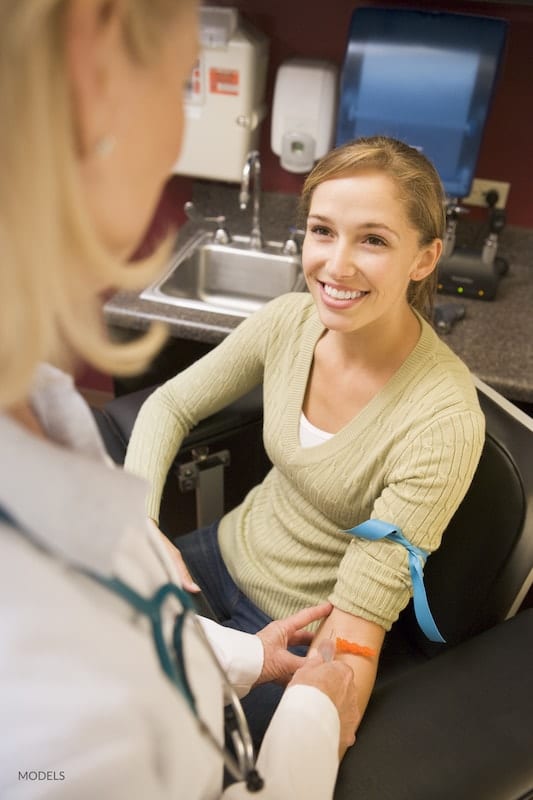 Happy woman getting blood drawn at her doctor's office.