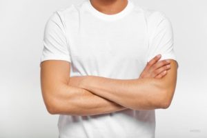 Fit man standing with his arms crossed over a white t-shirt.