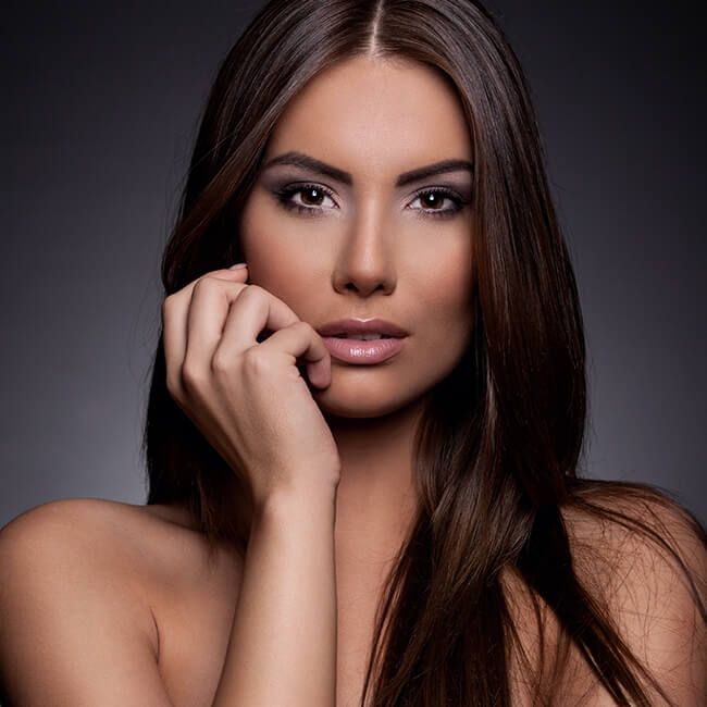 Brunette woman with long hair and hand resting on her face