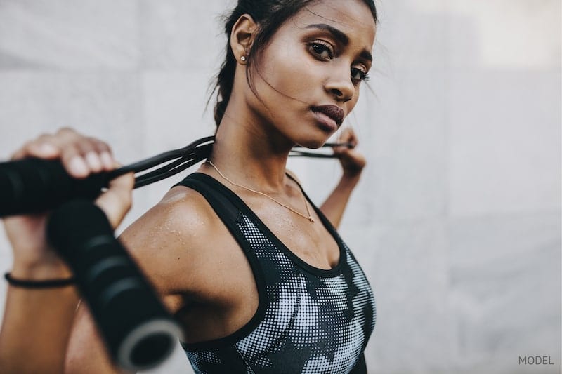 Fit woman holding a jump rope, wearing a sports bra.