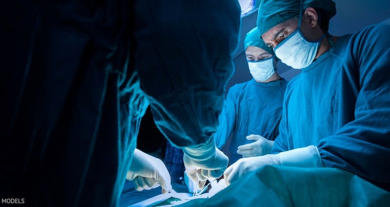 Group of surgeons performing a plastic surgery procedure in operating room.