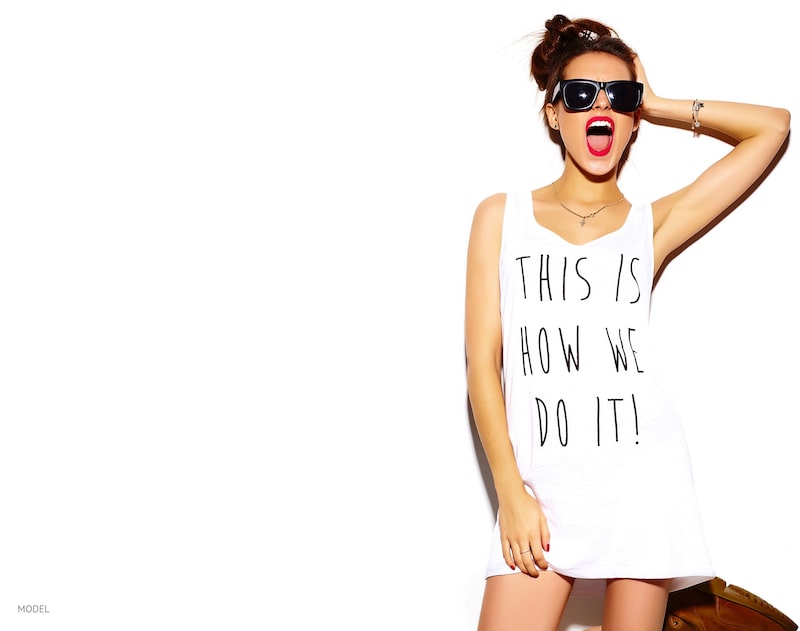 Young woman against a white wall wearing sunglasses and oversized t-shirt