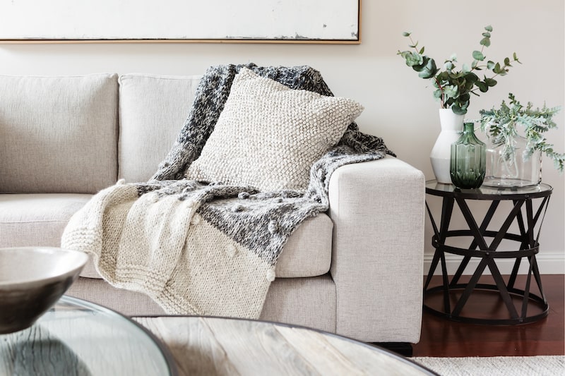 a couch with blankets, pillows, and an end table.