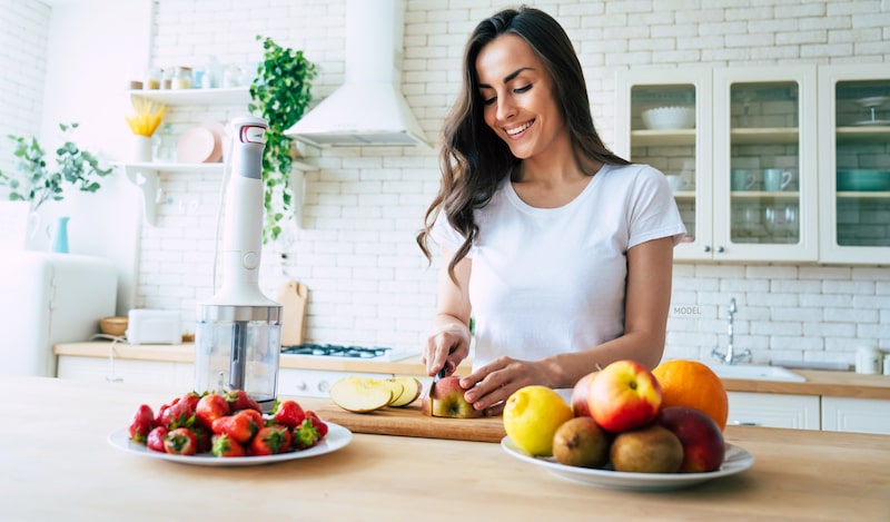 Woman cutting up fruit in kitchen