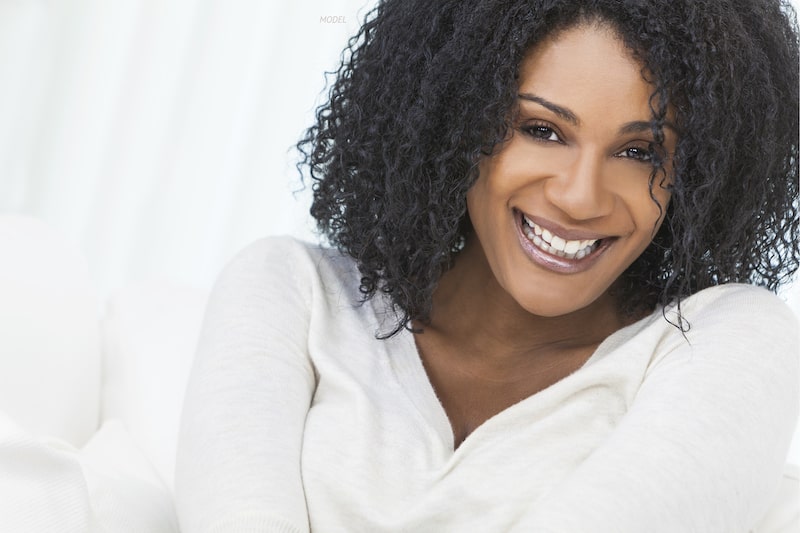 Smiling African American women leaning against a white couch.