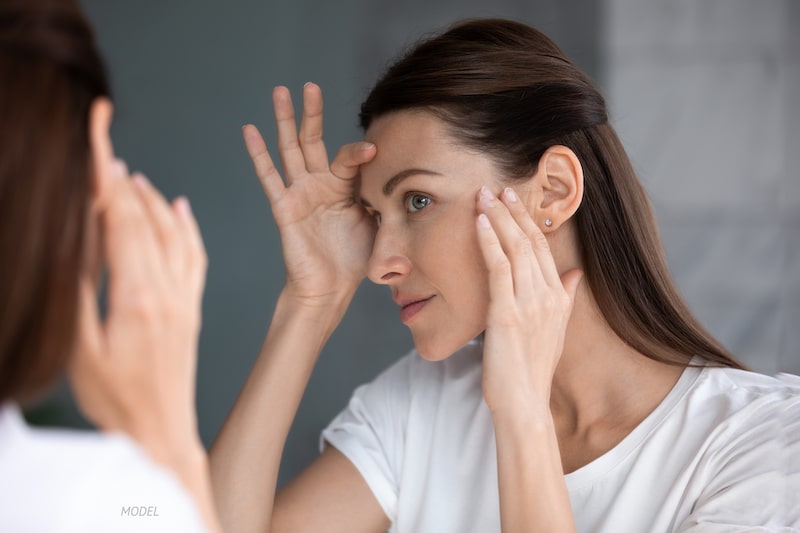 Women looking at her face in the mirror to check for wrinkles