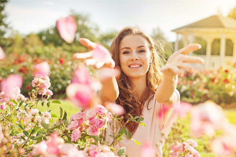 Woman tossing flower petals towards camera.