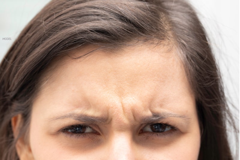 Close up of young woman with furrowed brow.