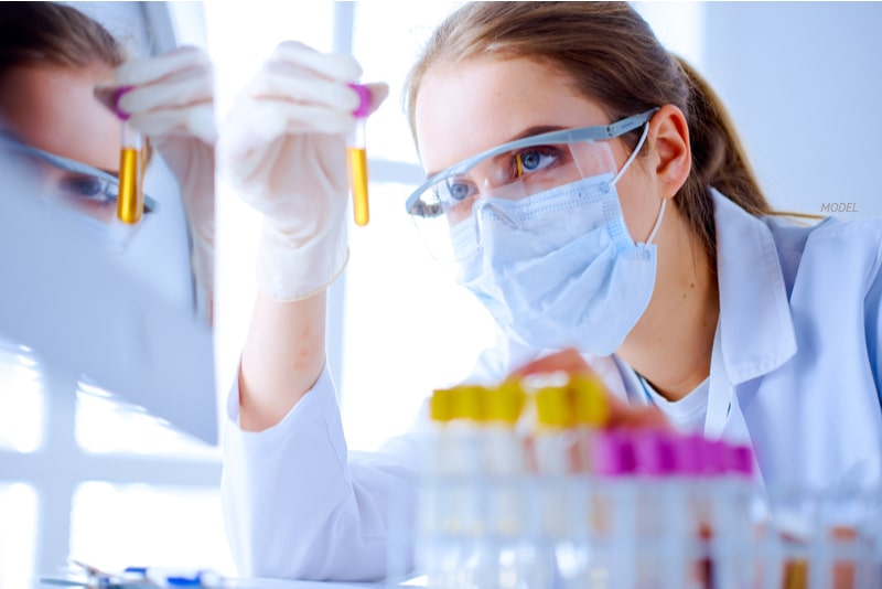 Young, female doctor is studying a vial in a laboratory.