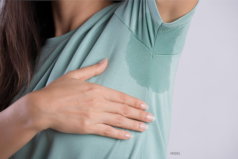 Woman with underarm sweat showing through her shirt.