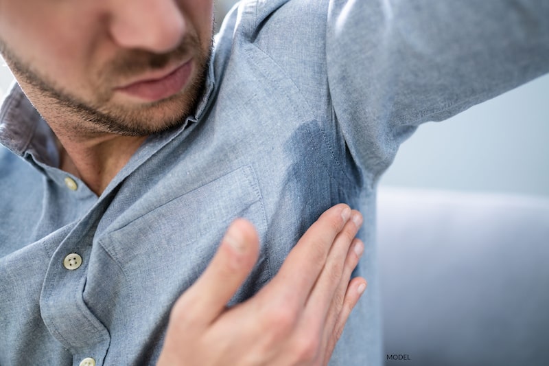 A man examines his excessive underarm sweating.