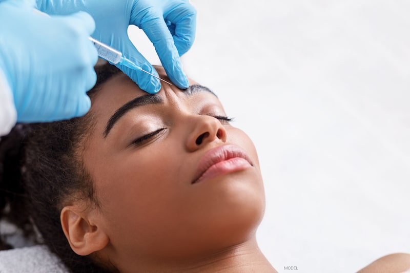 A woman receives BOTOX® Cosmetic between her eyebrows.