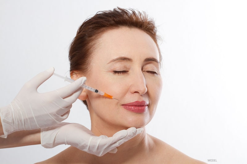 A mature woman receives an injectable facial filler to treat nasolabial folds.
