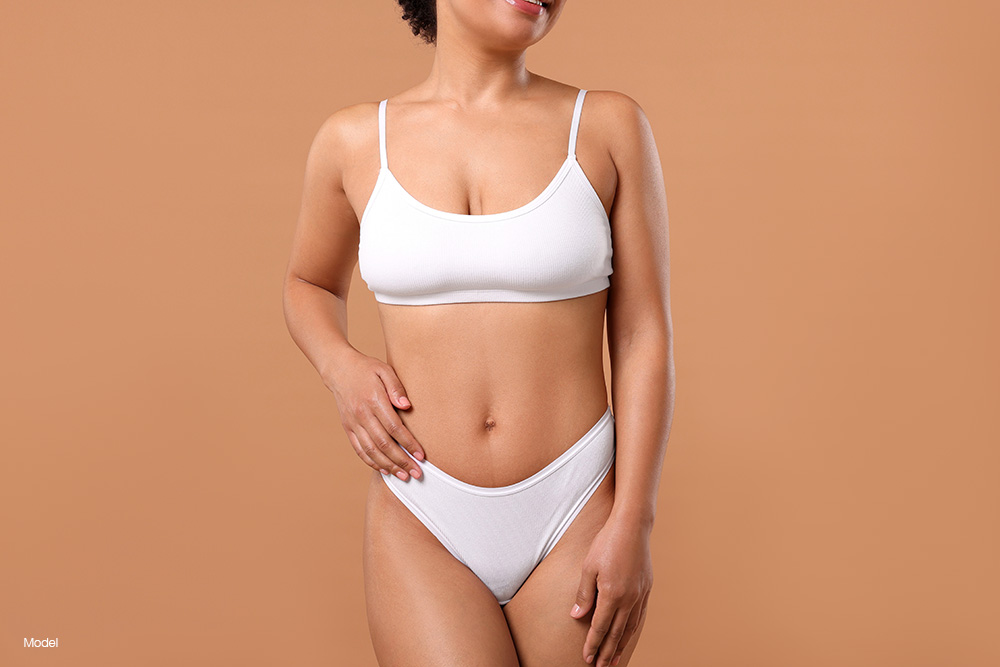 Curvy woman in white underwear against a brown backdrop