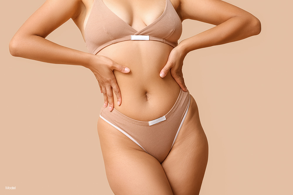 Curvy woman in tan underwear with the hands on her hips